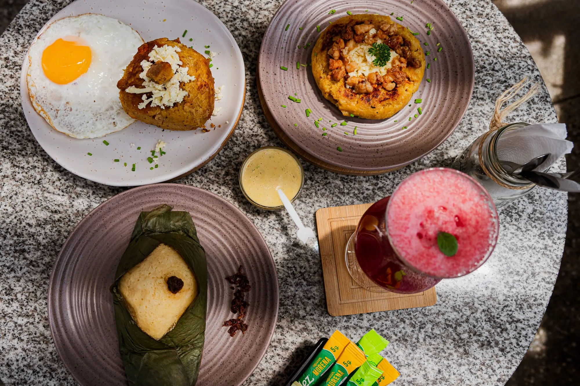 Mesa servida con desayunos, bolón y jugos de la carta de Tamarinda, La Carolina