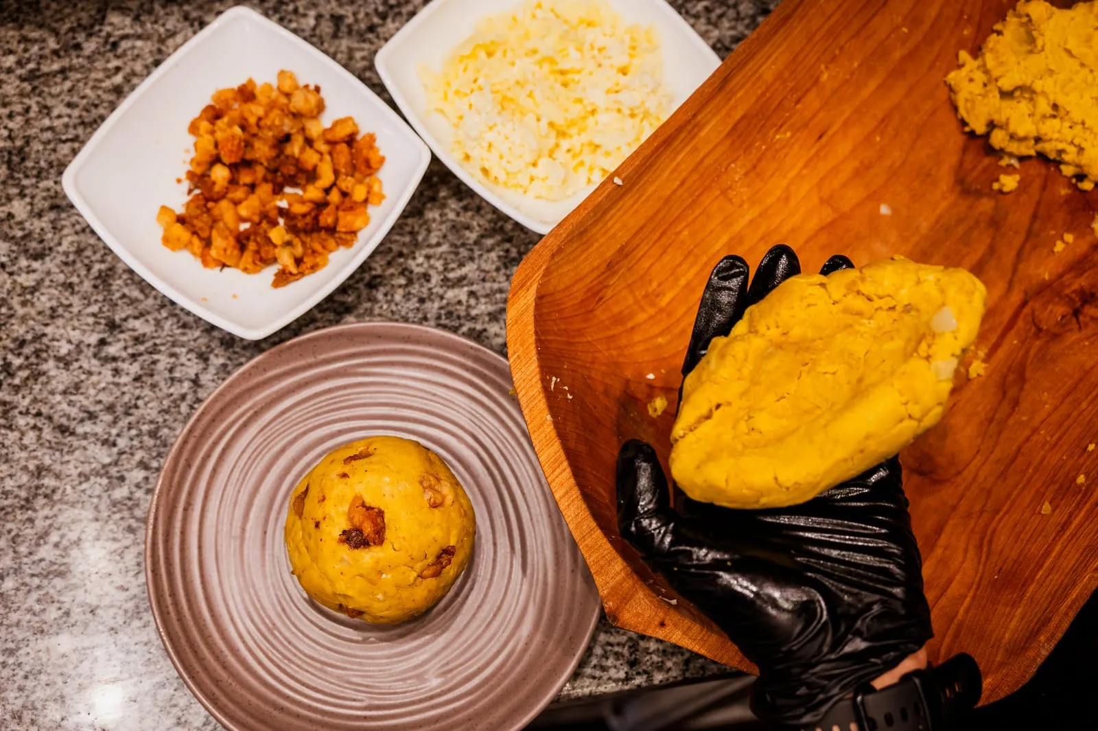 Manos preparando un bolón de verde en la cocina de Tamarinda, Quito